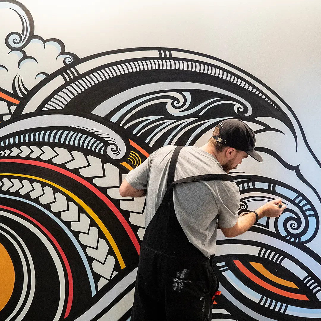 Finn Gerry Wilson painting one of six murals at PWC Auckland's Commercial Bay. Mural designed by Beck Wheeler.