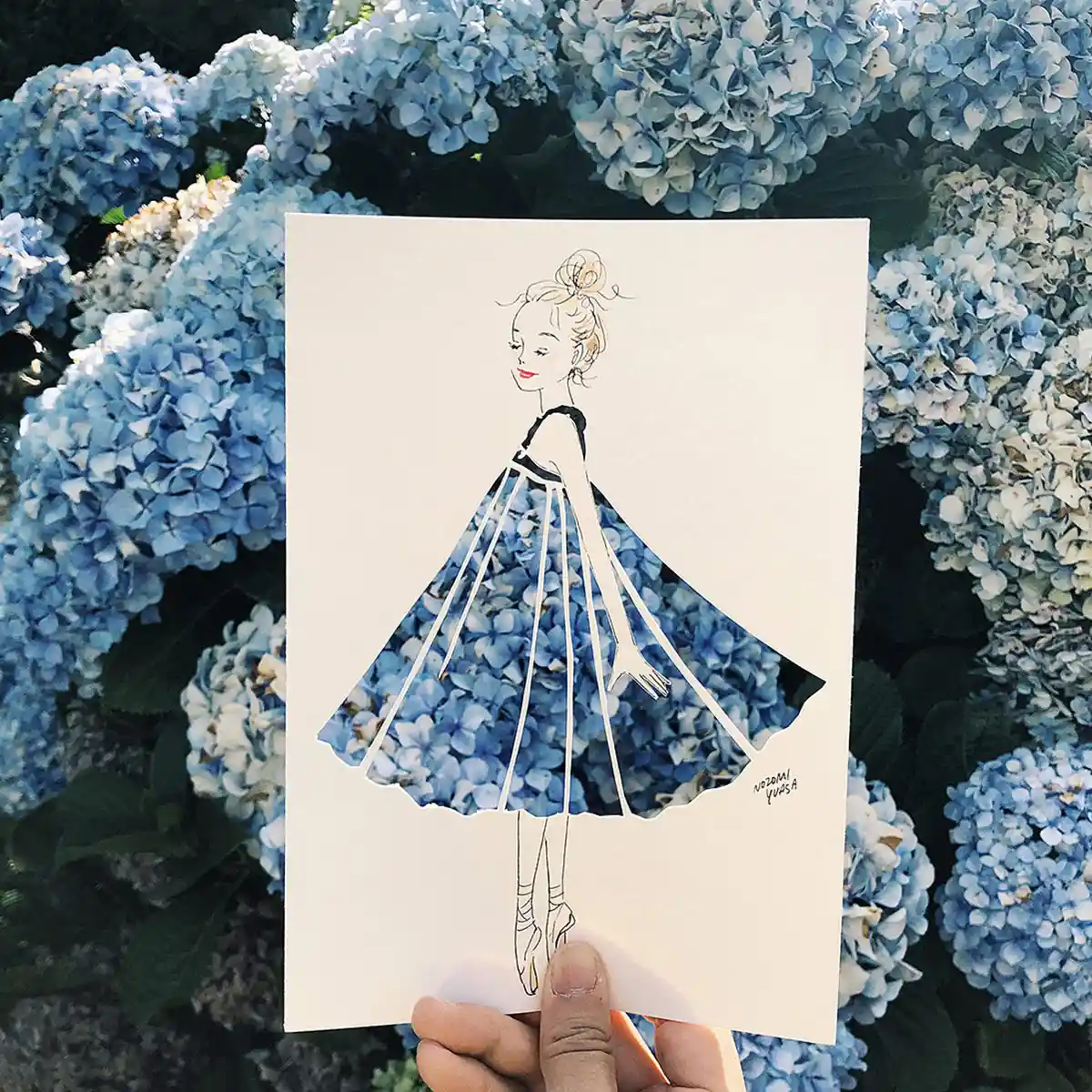 Illustrator Nozomi Yuasa creates an optical illusion with a stencil cut out of a woman revealing a backdrop of flowers.