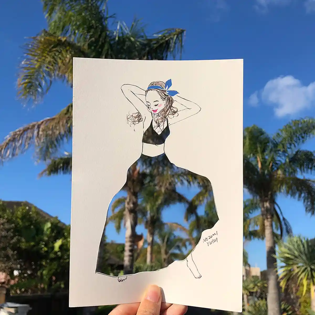 Illustrator Nozomi Yuasa creates an optical illusion with a stencil cut out of a woman revealing a backdrop of palm trees