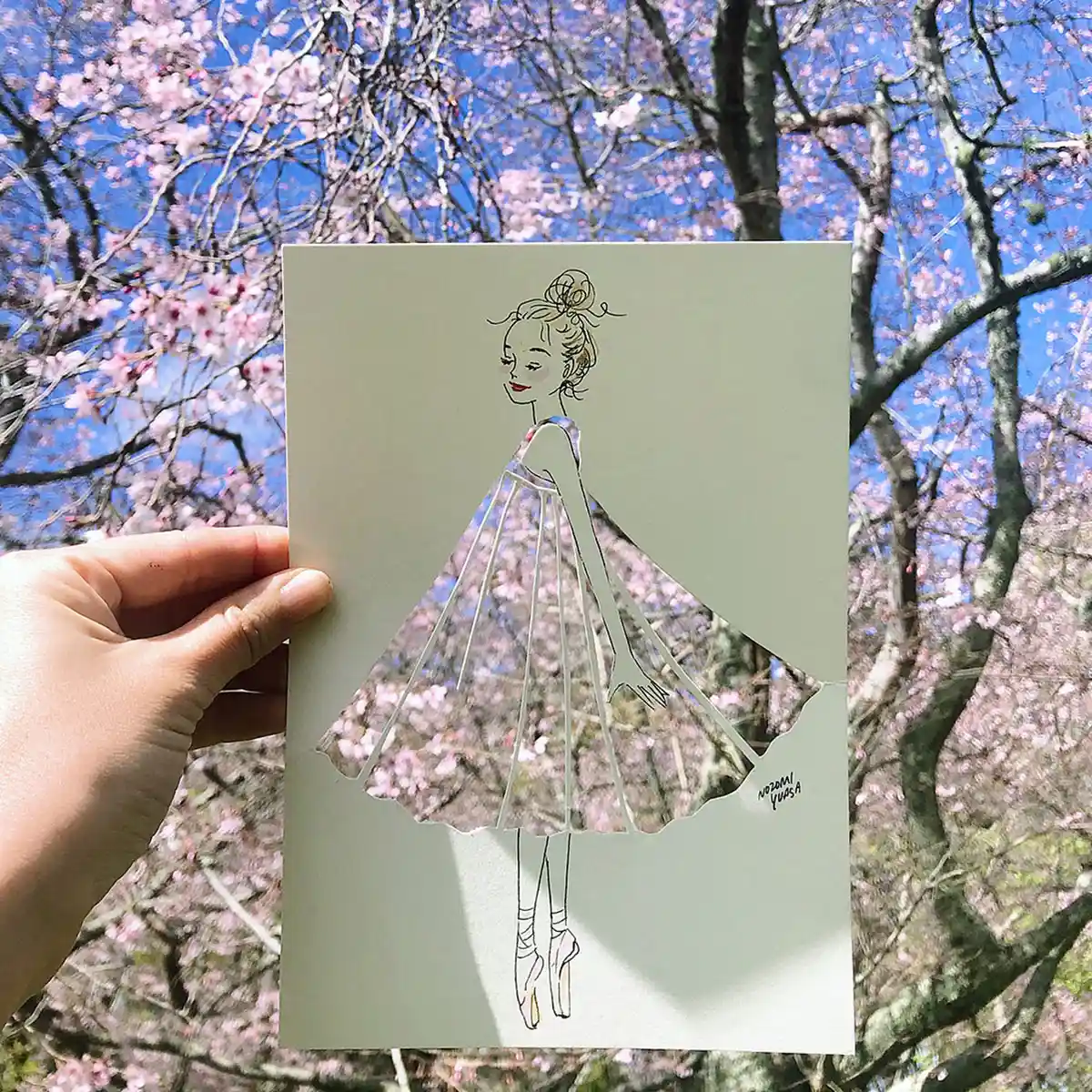 Illustrator Nozomi Yuasa creates an optical illusion with a stencil cut out of a woman revealing a backdrop of sakura