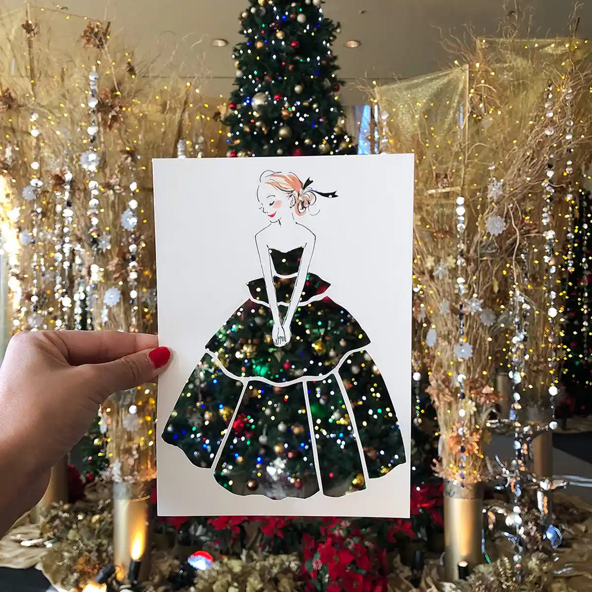 Illustrator Nozomi Yuasa creates an optical illusion with a stencil cut out of a woman revealing a backdrop of a Christmas tree